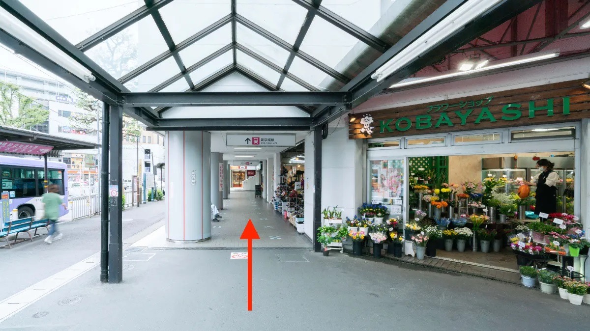 アーケードの歩道。右手の花屋「KOBAYASHI」の横を、赤い矢印の方向へ直進
