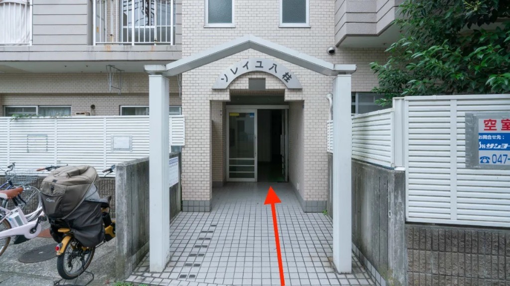 マンション「ソレイユ八柱」正面玄関。赤い矢印の先のガラス扉から入館